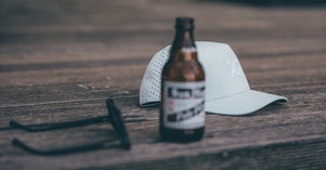 Brown bottle with label, white cap, and black object on a wooden surface