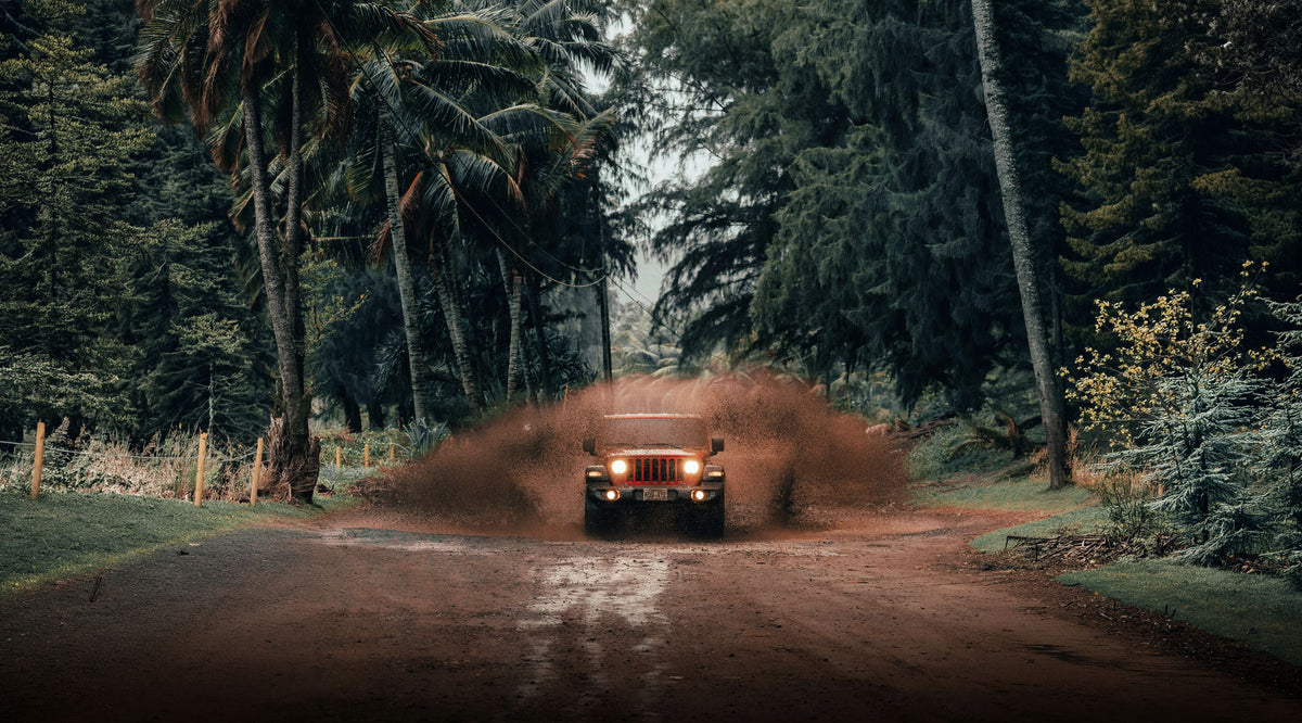 Jeep Wrangler blasting through a mud puddle on a jungle road